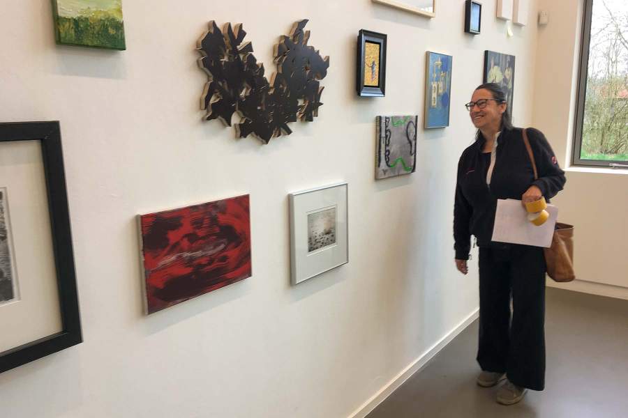 Maria Berkhout kijkt in CBK Emmen naar haar werk tussen heel veel ander werk van kunstenaars uit Emmen en omgeving